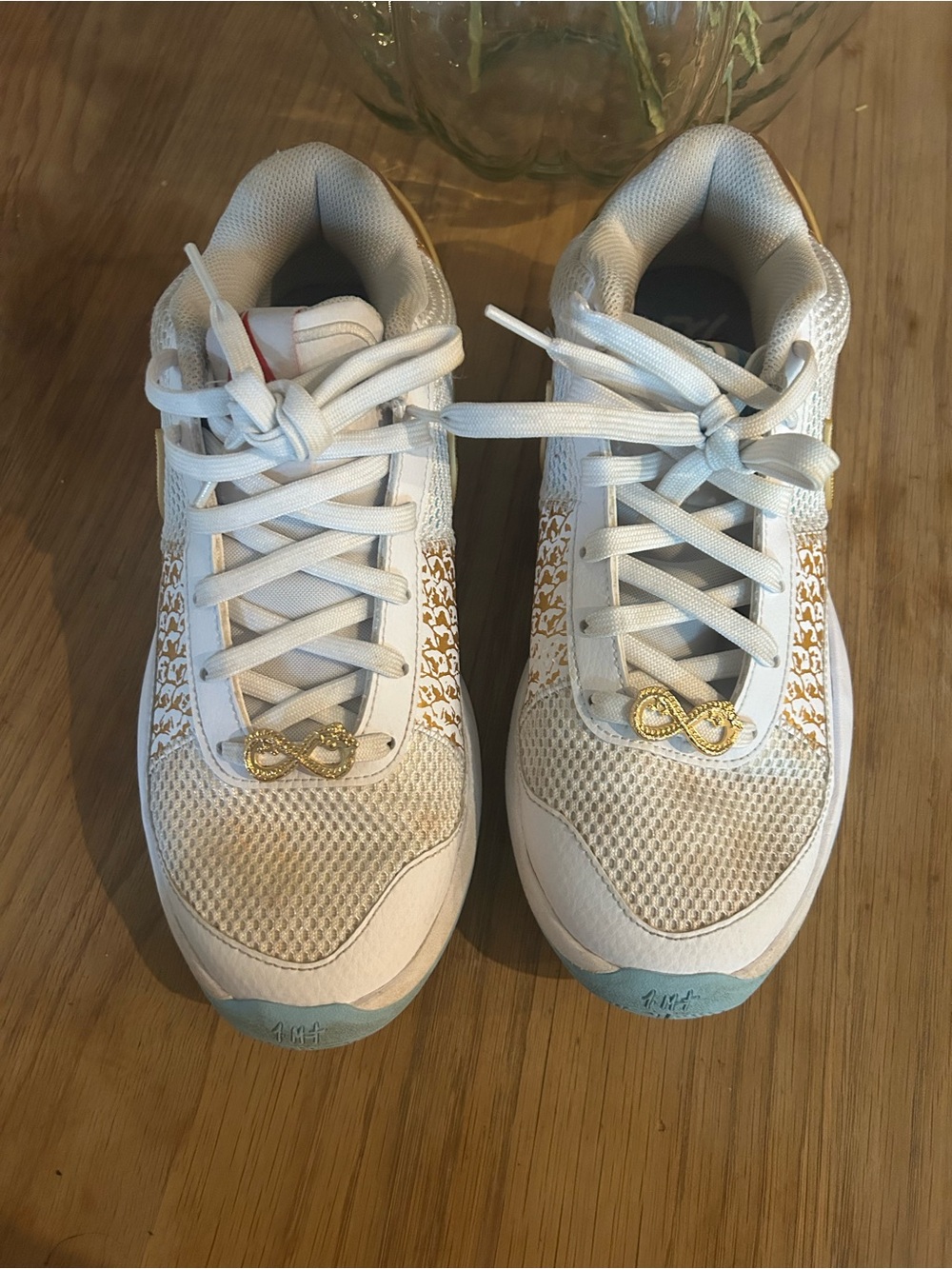 Nike Kobe white sneakers with gold accents and gold infinity symbols on the lace